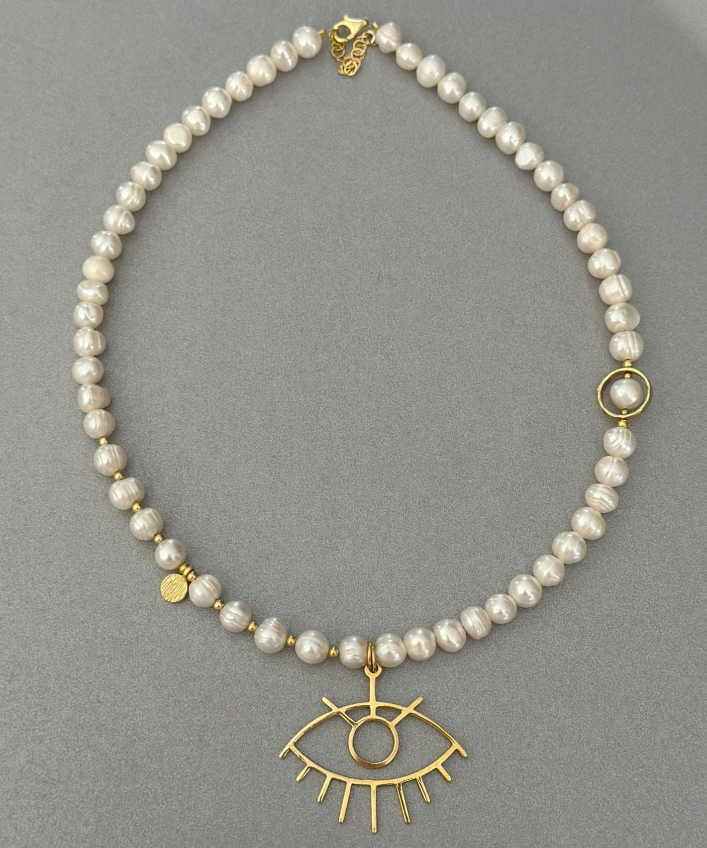 Baroque Pearl Silver Eye Necklace with gold eye pendant on grey background