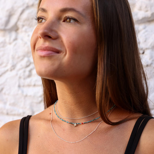 Model wearing the Birdie Minimal Silver Necklace with an elegant design, layered with delicate complementary necklaces.