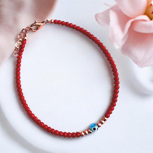 Elegant coral gemstone bracelet featuring a delicate mini evil eye charm, perfect for showcasing style and charm.