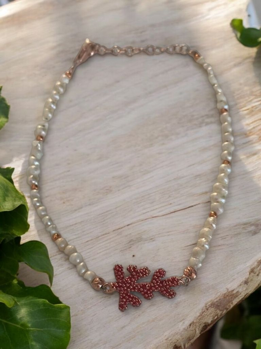Elegant freshwater pearl bracelet with silver coral charm on a wooden background, ideal for beach-inspired looks.
