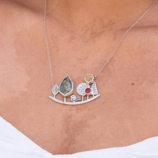 Close-up of a Landscape Silver Necklace worn on a neck, featuring intricate tree and gemstone designs.
