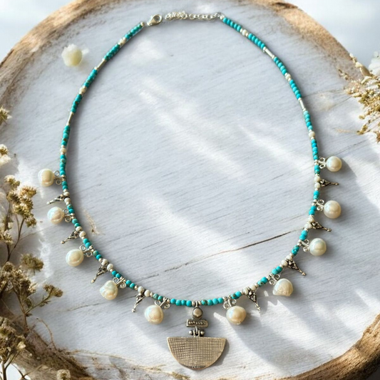 Selene Turquoise Gemstone and Pearl Necklace with delicate silver accents, displayed on a rustic wooden surface
