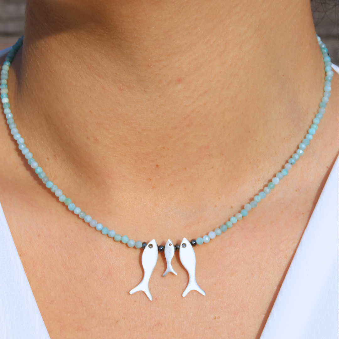 Amazonite gemstone necklace featuring three silver fish pendants, elegantly worn for a casual yet stylish look.