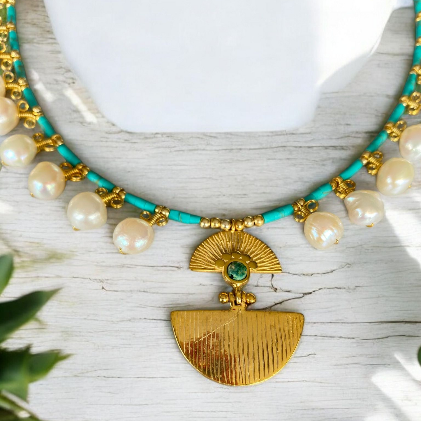 Ariadne Necklace with Pearl and Turquoise Gemstone in Sterling Silver 14K Gold Plated placed on a light wooden background.