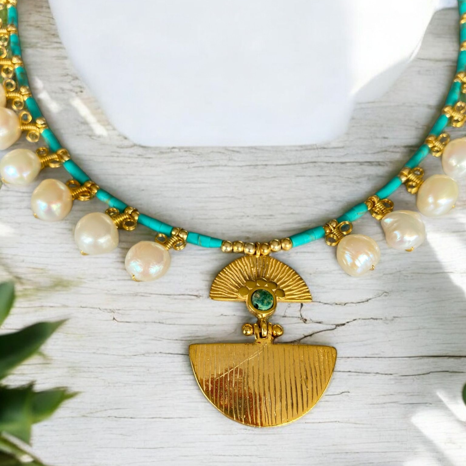 Ariadne Necklace with Pearl and Turquoise Gemstone in Sterling Silver 14K Gold Plated placed on a light wooden background.