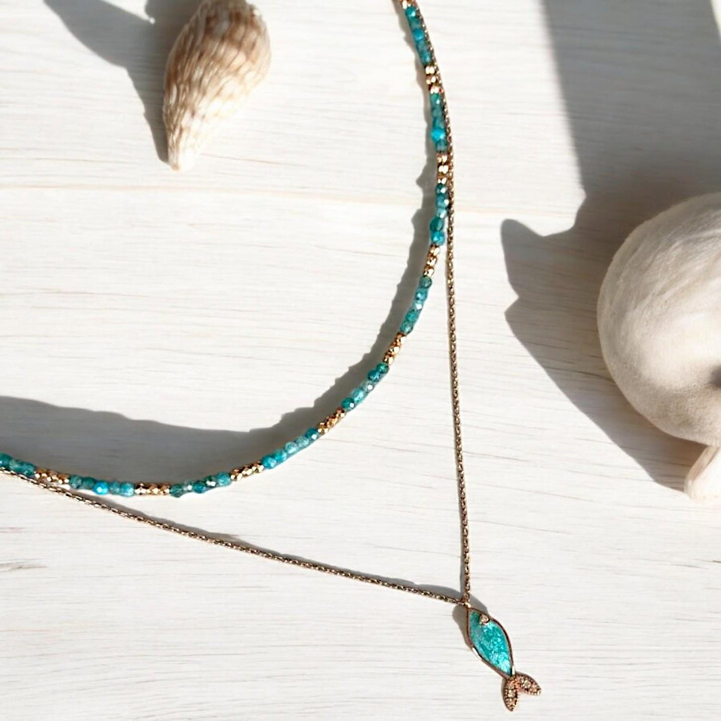 Azure silver fish pendant necklace and apatite gemstone jewellery set beautifully displayed on a soft wooden surface.