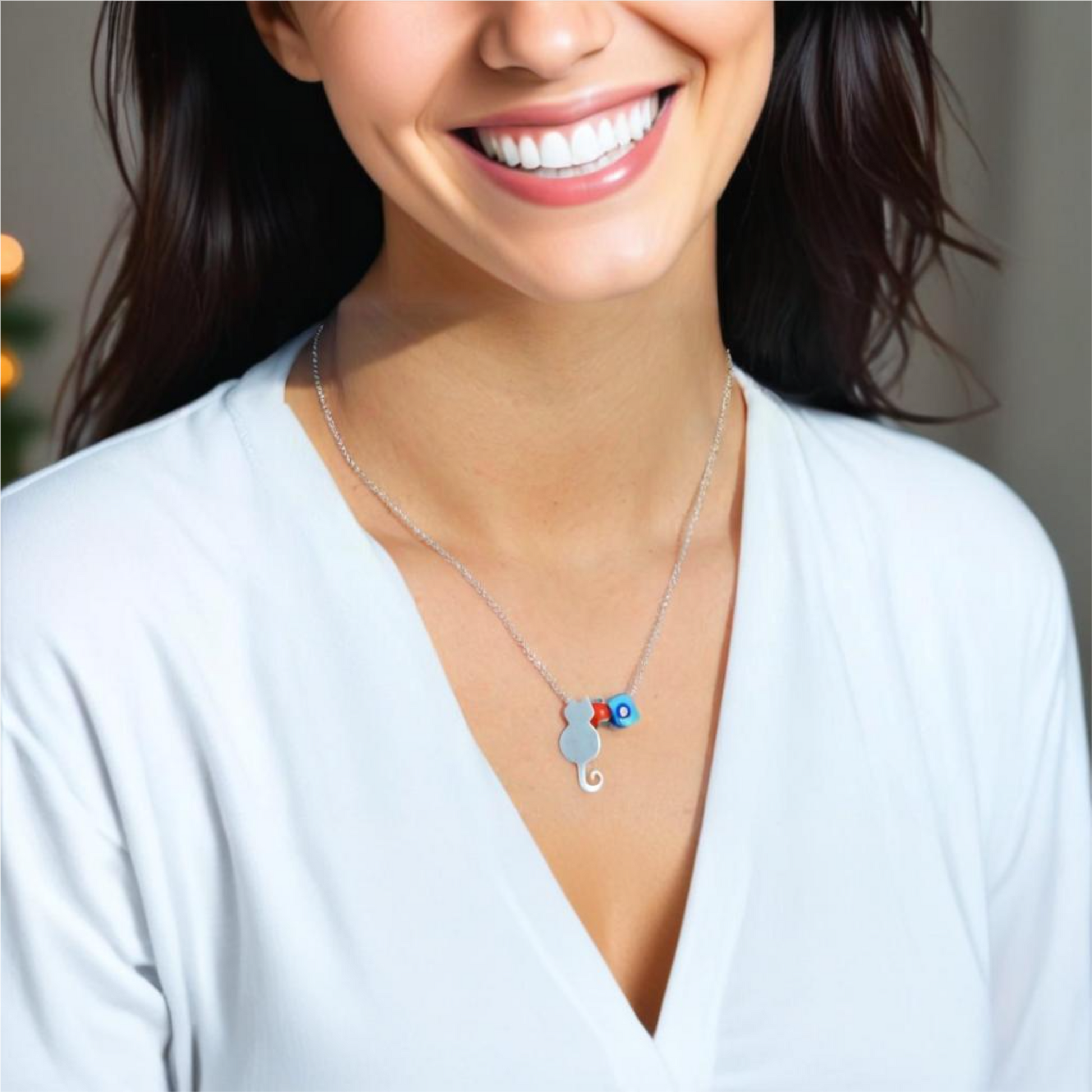 Woman wearing a Cat and Evil Eye silver necklace with a charming smile, highlighting unique jewellery design.