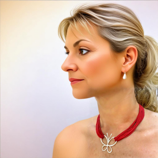 Coral gemstone layered necklace featuring a silver butterfly pendant, elegantly worn by a woman with blonde hair.