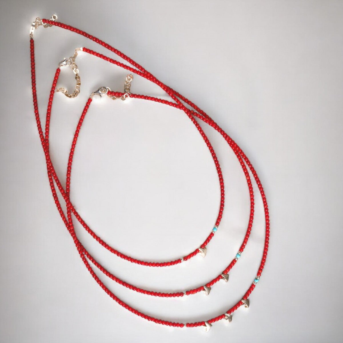 Elegant minimalist necklace featuring coral gemstone beads and 925 sterling silver bird pendant on a white background.