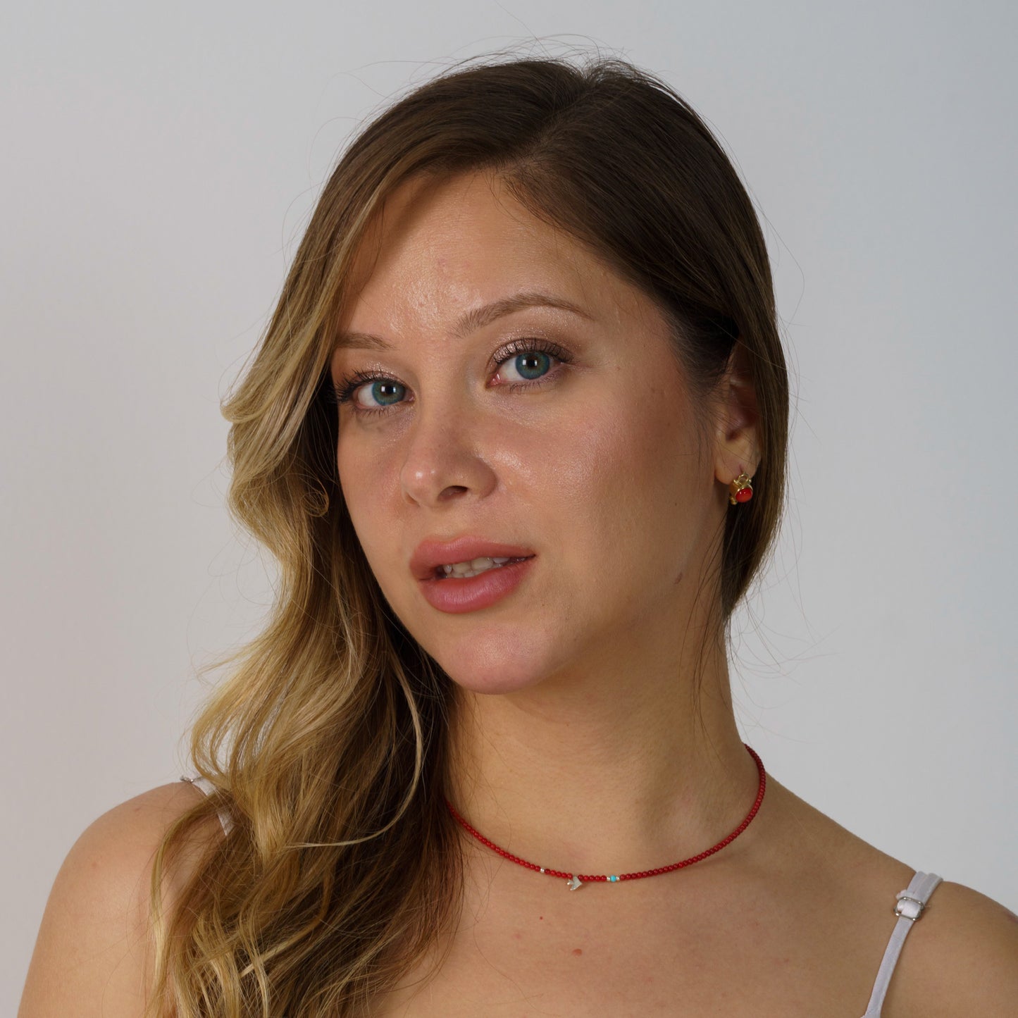 Minimalist coral gemstone necklace with 925 sterling silver bird pendant, worn by a woman with light hair and neutral background.