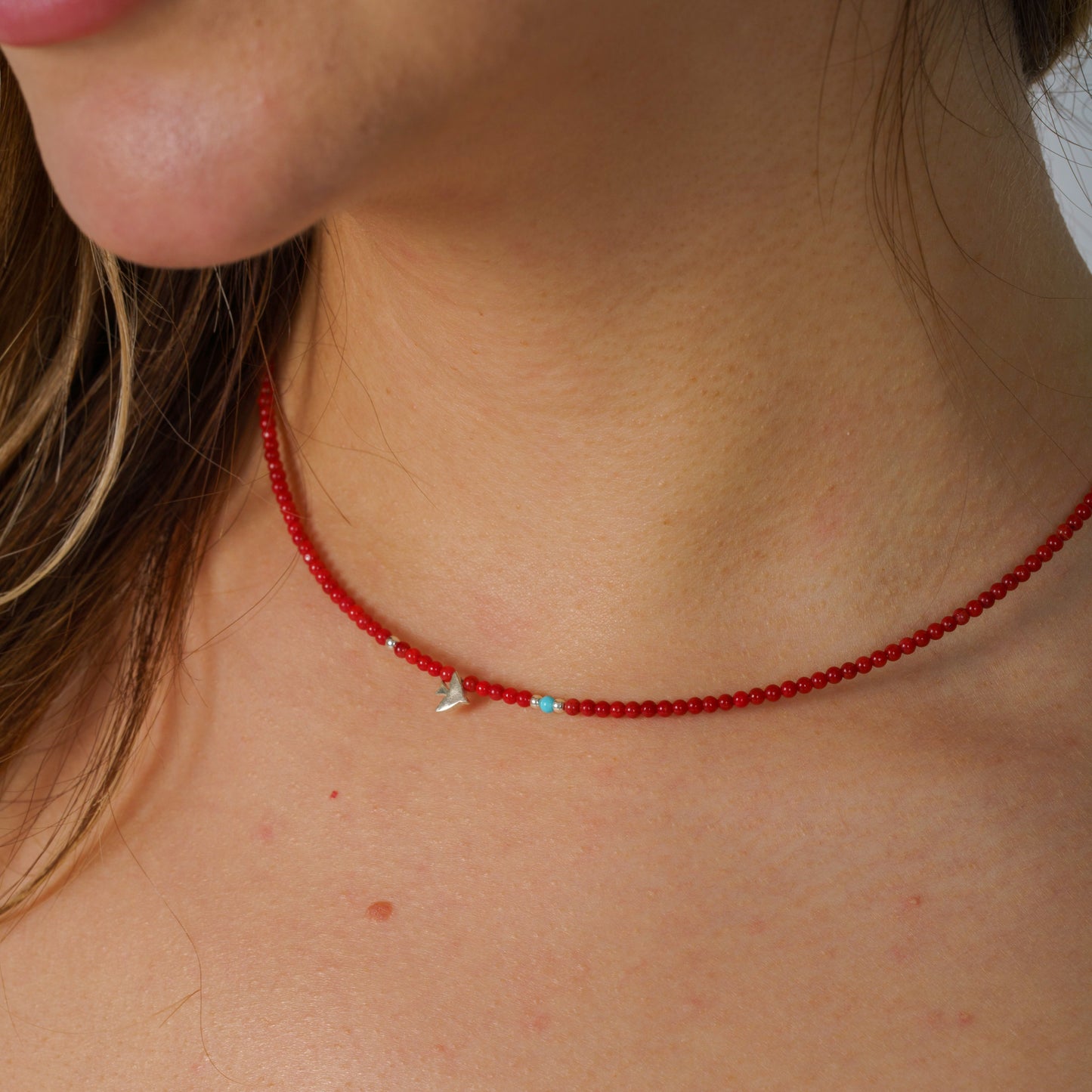 Minimalist coral gemstone necklace featuring a sterling silver bird pendant, elegantly crafted for a sophisticated look.