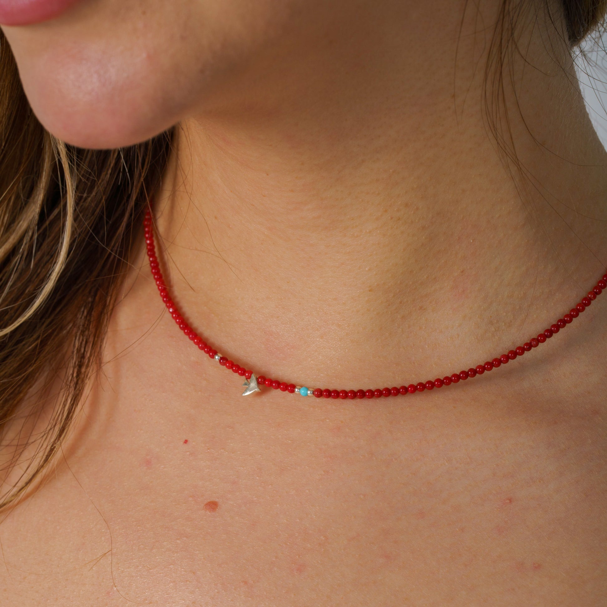 Minimalist coral gemstone necklace featuring a sterling silver bird pendant, elegantly crafted for a sophisticated look.