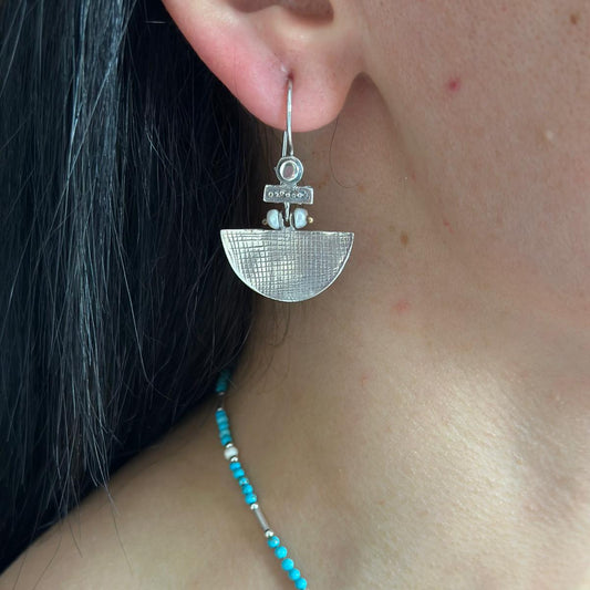 Close-up of stylish Selena Silver Earrings with geometric design worn by a person.