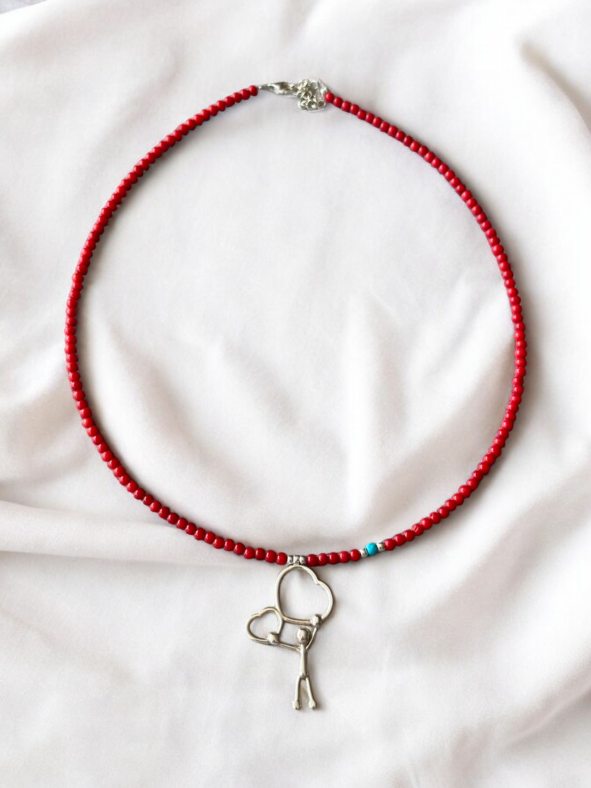 Two Hearts Coral Gemstone Necklace with silver charm on light fabric